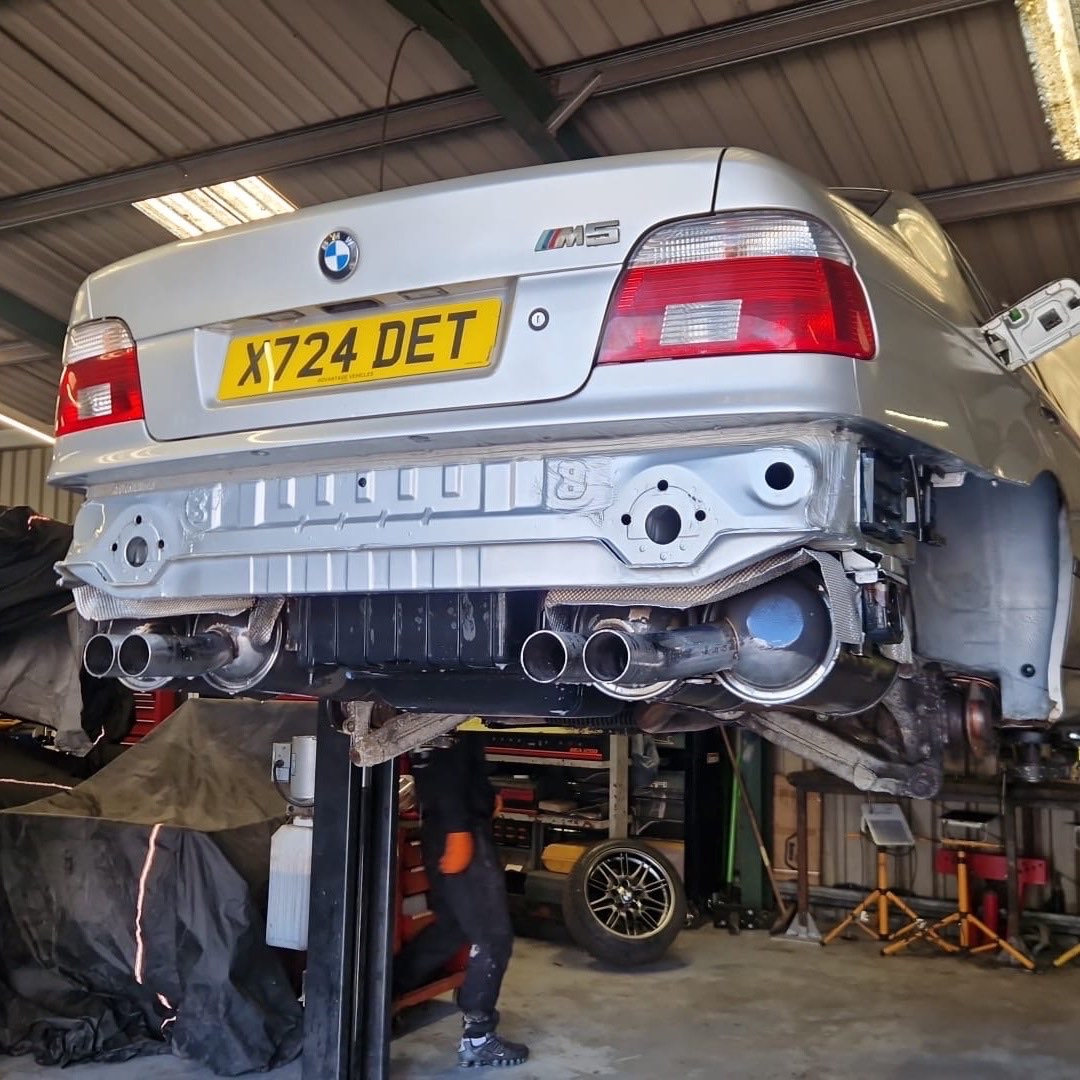 The rear on the lift with the bumper off, and the factory quad-outlet exhaust.